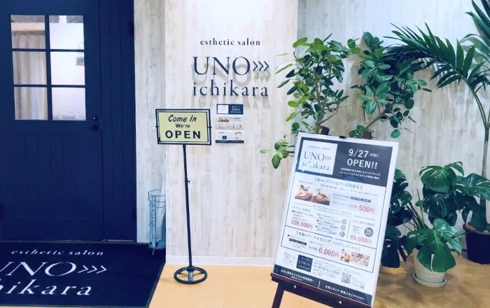 サロンの入口。ネイビーの扉と「esthetic salon UNO>>>ichikara」の看板。