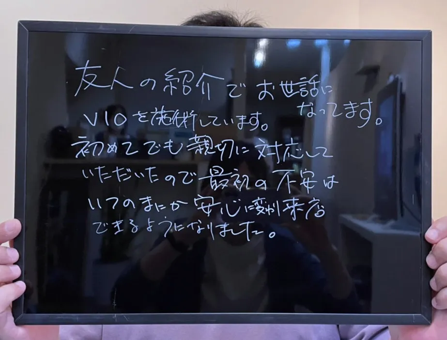 手書きのボードを両手で持つお客様。顔は写っていません。